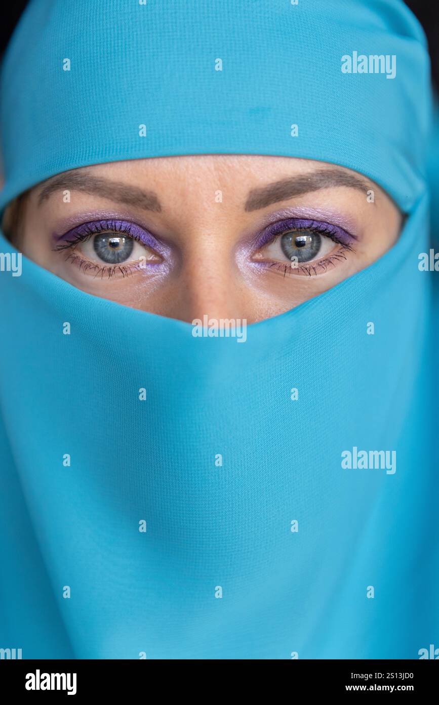 Giovane donna con gli occhi blu che indossa un tessuto turchese, che guarda la fotocamera. Foto Stock