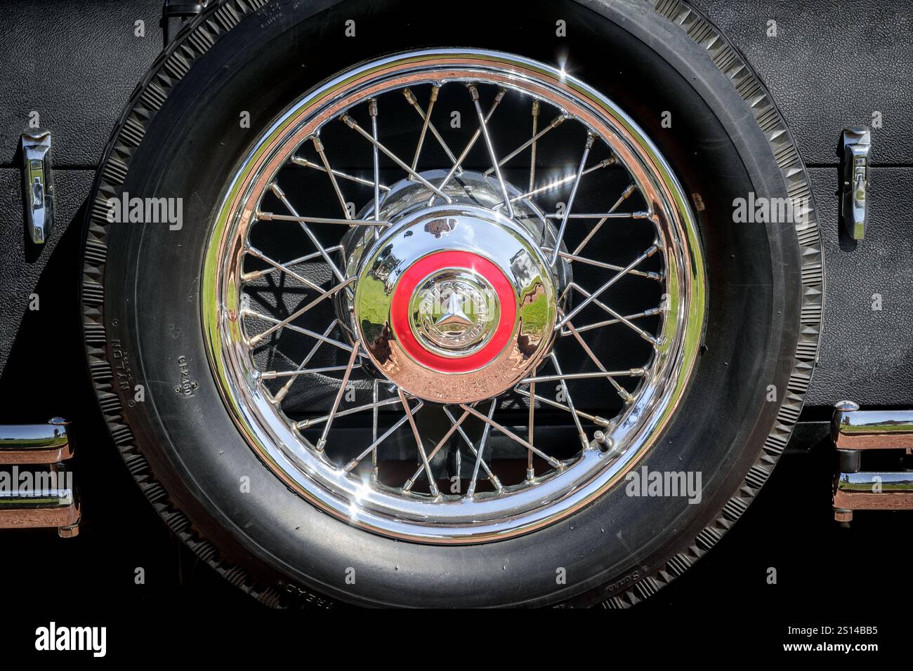 Lisbona, Portogallo - 29 settembre 2024: Vista ravvicinata della ruota di scorta Mercedes-Benz 370 S Mannheim sport cabriolet fissata al bagagliaio nelle giornate di sole. Cerchi in filo metallico cromati con bagliori solari, iconico marchio a tre punte e logo Mercedes-Benz Foto Stock