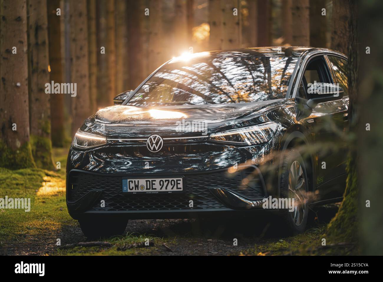 Auto nera nella foresta con raggi solari e riflessi sulla superficie, veicolo condiviso Deer Mobility, auto elettrica VW ID5, Foresta Nera, Germania, E. Foto Stock