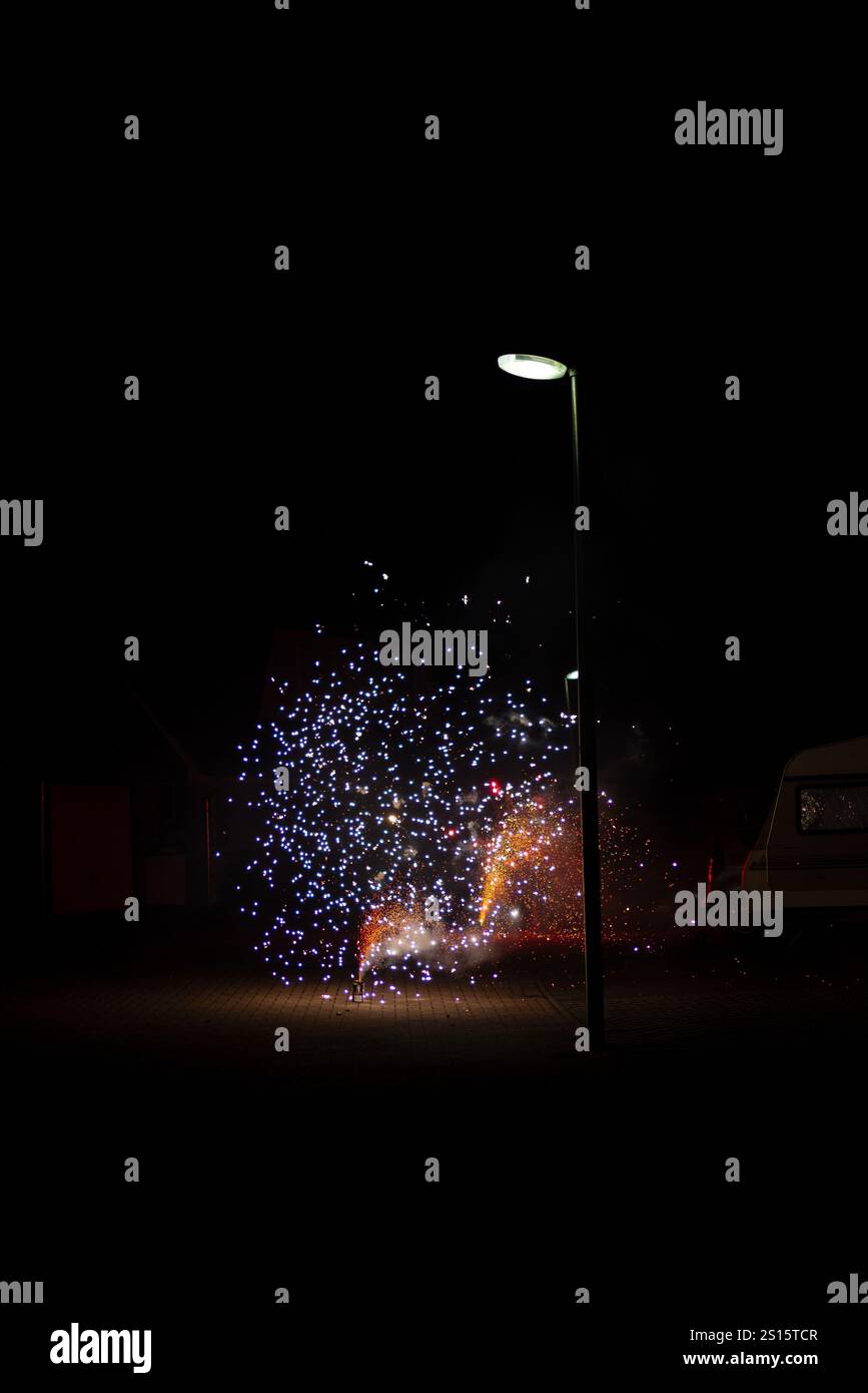 Incredibile spettacolo di fuochi d'artificio catturato durante le celebrazioni di Capodanno 2025, illuminando il cielo notturno su un quartiere residenziale Foto Stock