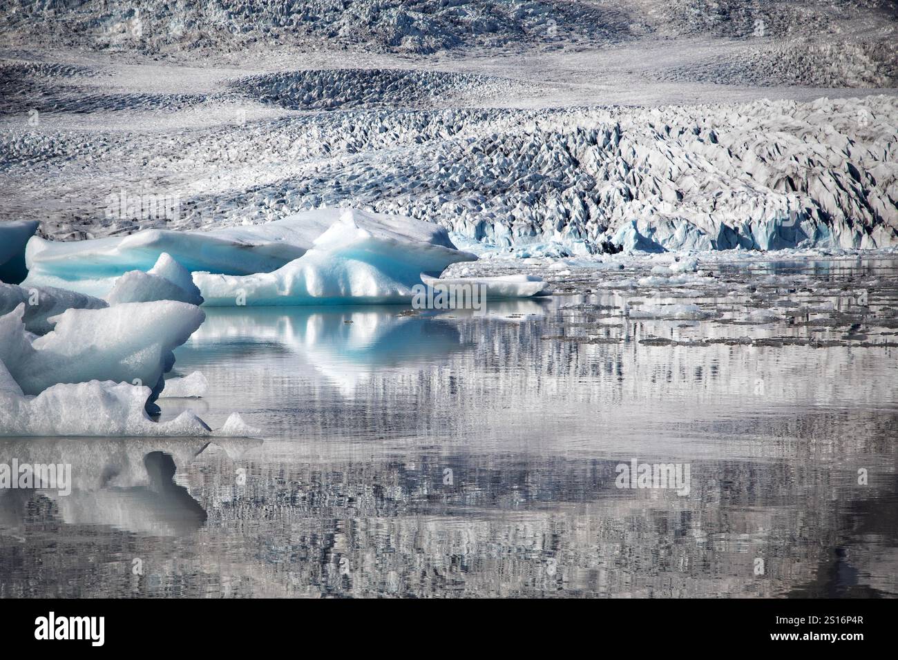 La maestosa cascata del ghiacciaio Fjallsjökull scende dalle aspre montagne degli altopiani, la sua distesa ghiacciata incontra il sereno lago glaciale. Foto Stock