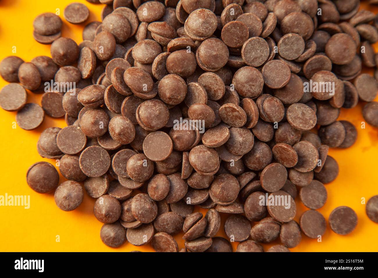 Primo piano delle gocce di cioccolato su sfondo giallo, grossi pezzi. Foto Stock