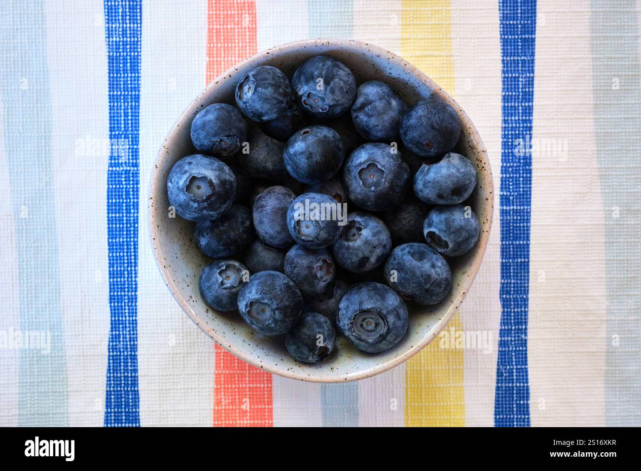 Mirtilli freschi in una ciotola rotonda su un panno da tavola a righe, un frutto sano ricco di sostanze nutritive con una serie di benefici per la salute. Foto Stock