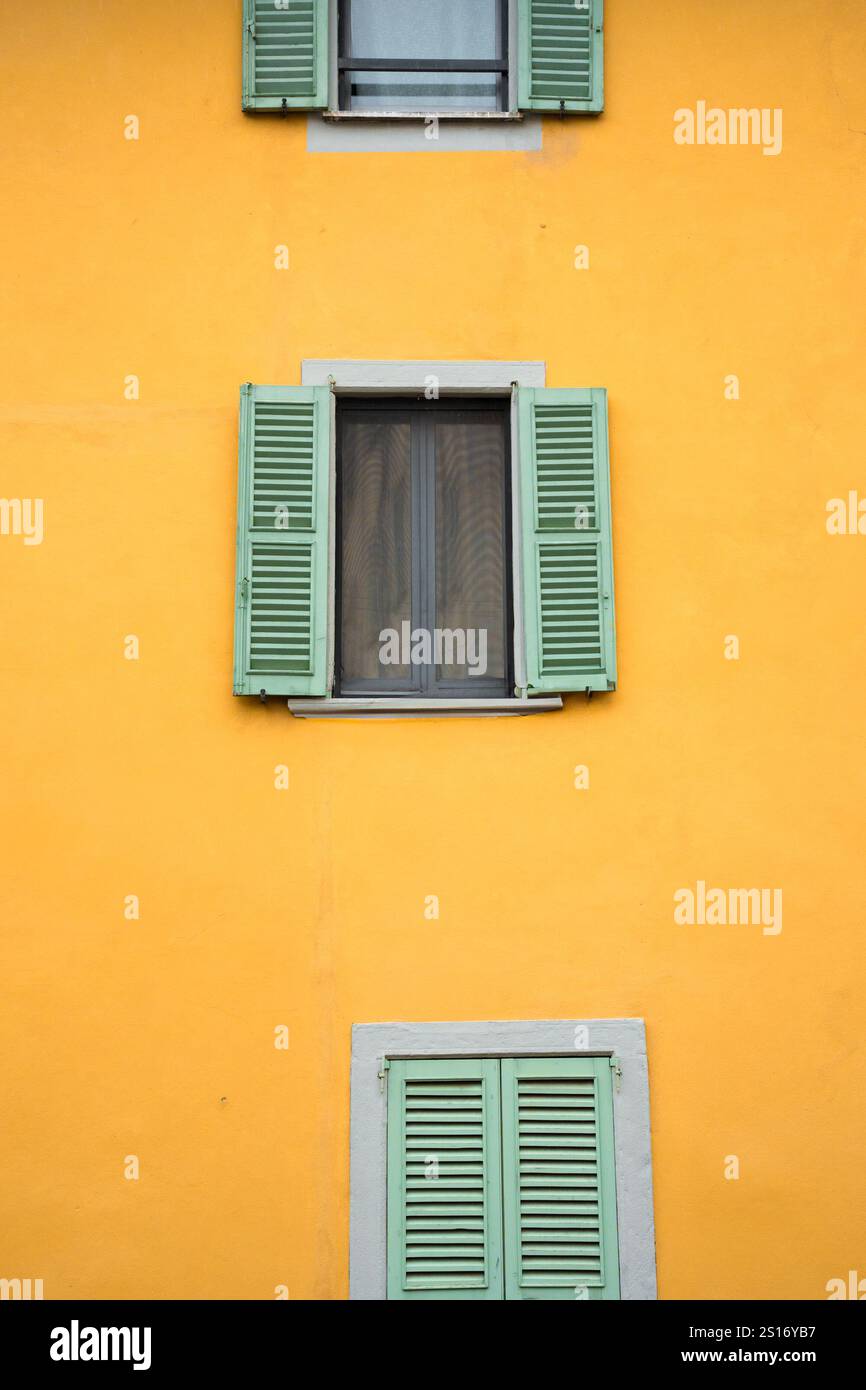 Facciata di un vecchio edificio giallo con finestre con persiane Foto Stock