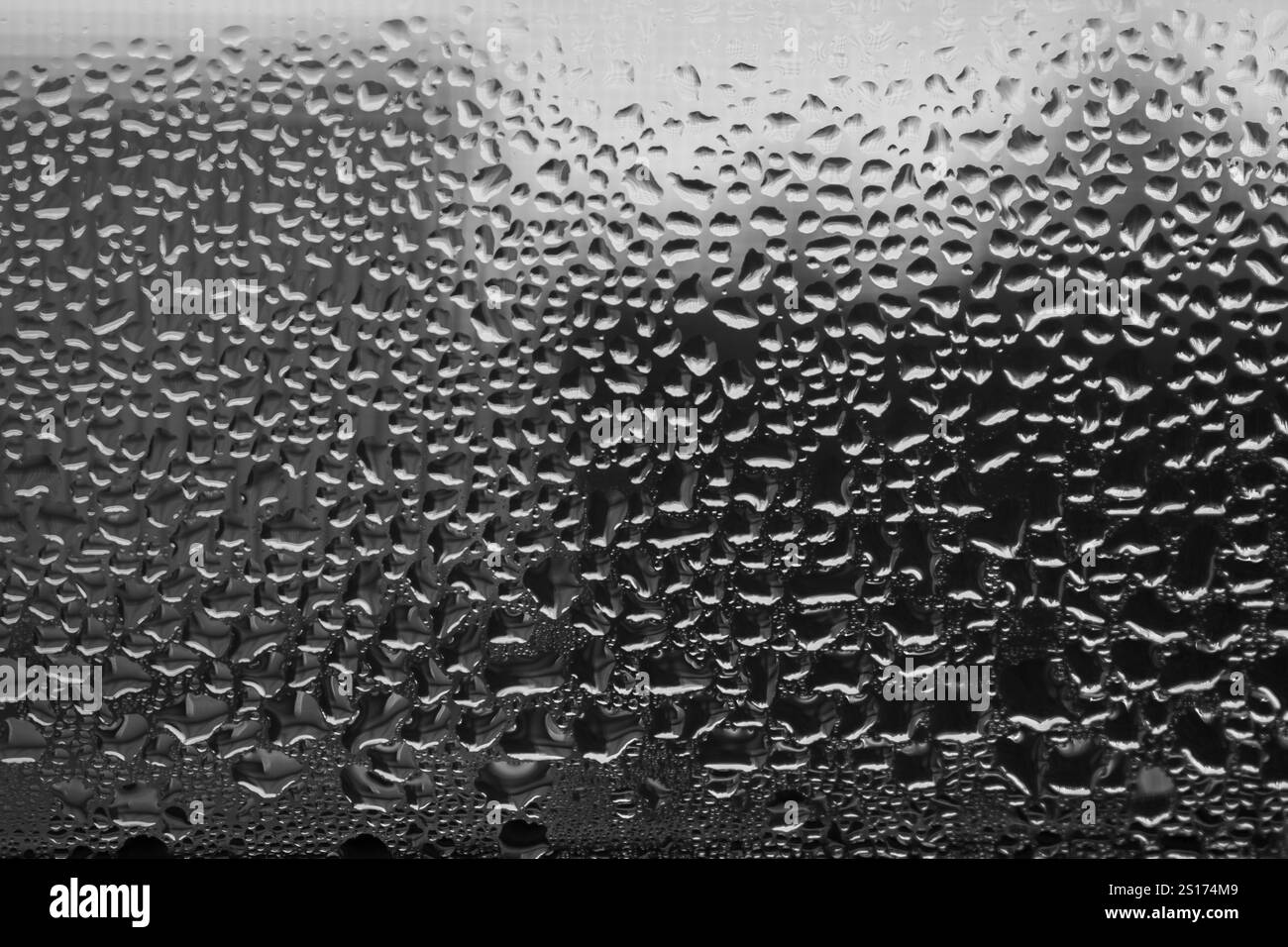 Gocce d'acqua soffici su una finestra di vetro, sfondo astratto dell'acqua, tappezzeria scura con gocce Foto Stock