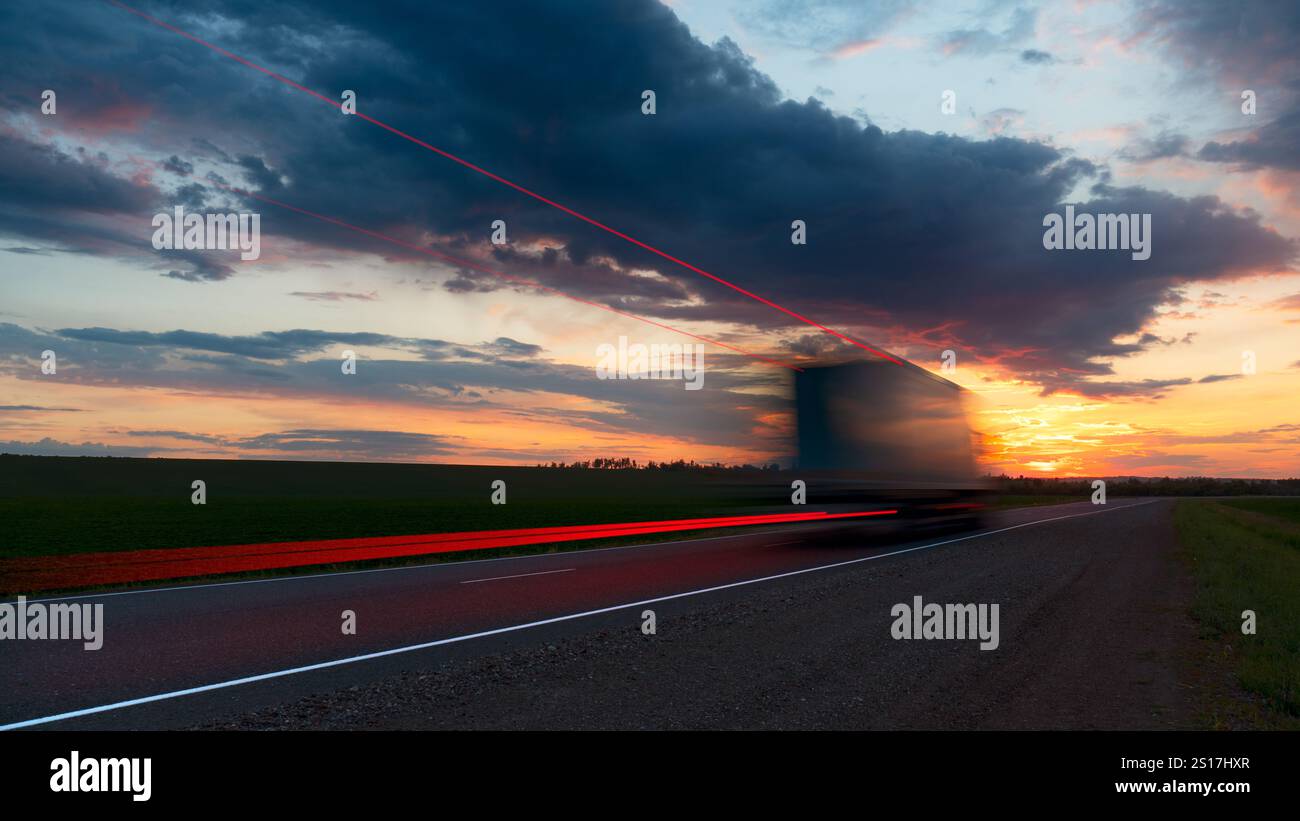 Sfocatura. Carrello in movimento su autostrada ad alta velocità. Nelle nuvole del cielo. Tramonto del sole all'orizzonte giallo-rosso brillante. Consegna del carico. Foto Stock
