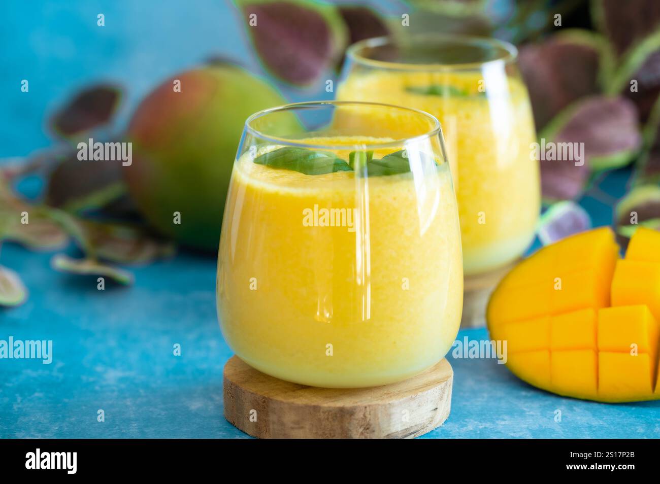 Freschi lassi di mango in bicchieri su sfondo blu con spazio per le copie. Indiano sana detossica ayurvedica bevanda fredda con mango. Lassi di freschezza a base di yogur Foto Stock