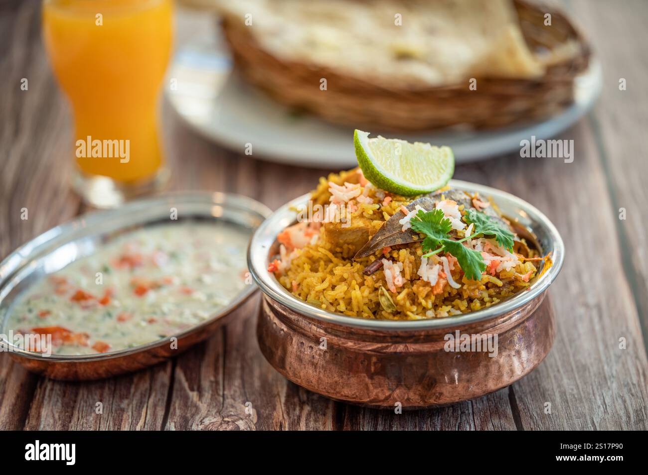 Pulao biryani indiano piccante in ciotola dorata con riso basmati indiano con curry di carne di pollo Ramadan Kareem, Eid. Recipiente da portata in ottone con dorso bianco Foto Stock
