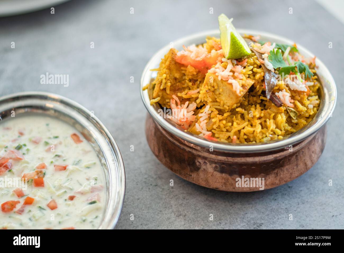 Pulao biryani indiano piccante in ciotola dorata con riso basmati indiano con curry di carne di pollo Ramadan Kareem, Eid. Recipiente da portata in ottone con dorso bianco Foto Stock