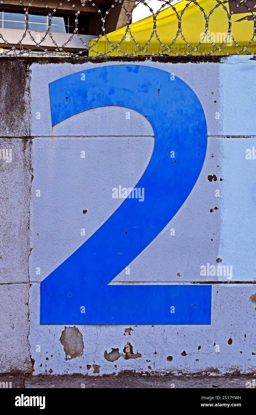 Numero due in blu su un muro bianco Foto Stock