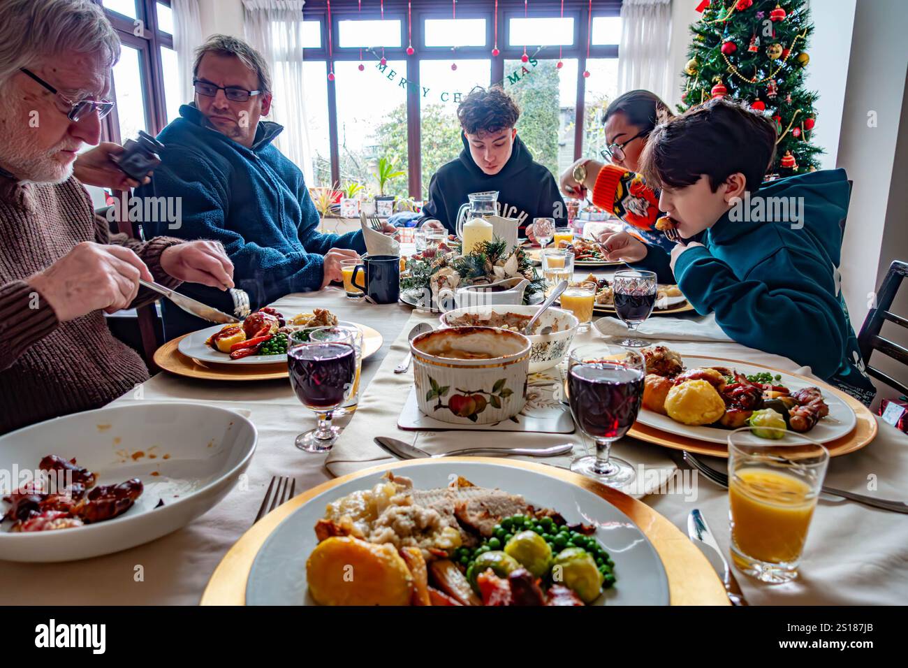 Una famiglia si siede insieme e si gusta una cena di Natale arrosto. Foto Stock