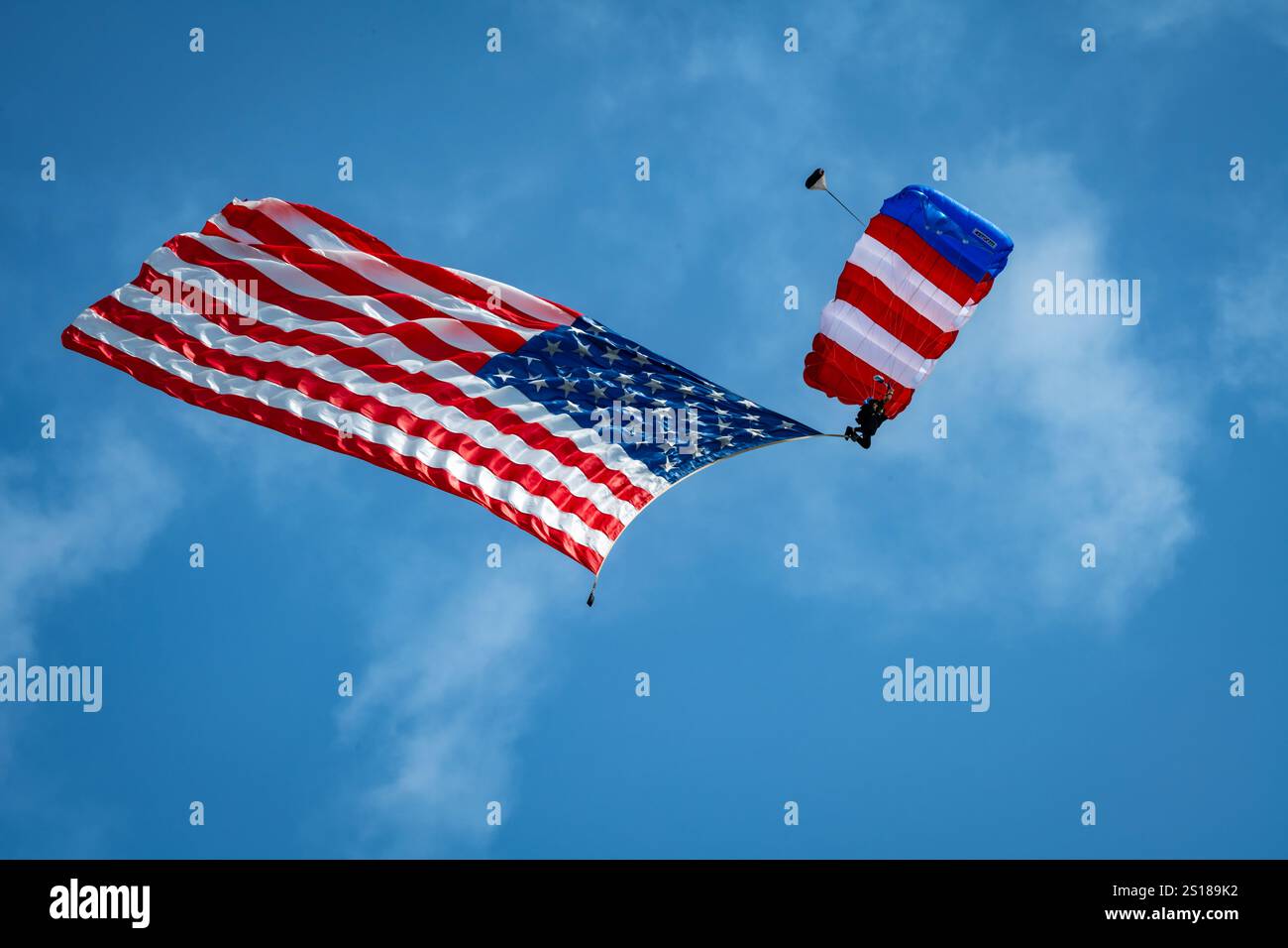 Un paracadutista scende sventolando la bandiera americana durante l'esecuzione dell'inno nazionale degli Stati Uniti all'esposizione aerea Experimental Aircraft Association AirVenture di Oshkosh, Wisp., 22 luglio 2024. L'EAA ha ospitato la sua convention annuale sull'aviazione della durata di una settimana, con numerose manifestazioni di aerei militari e manifestazioni aeree. (Foto U.S. Air Force di Daniel Peterson) Foto Stock