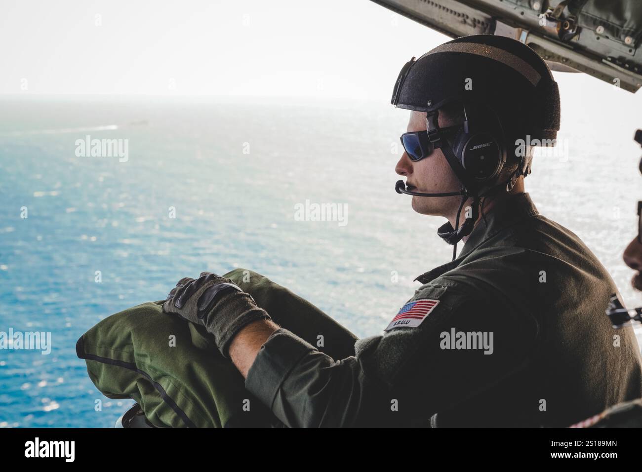 David Narkis, un tecnico di manutenzione dell'aviazione assegnato alla Coast Guard Air Station Barbers Point, siede sulla rampa di poppa di un aereo HC-130 Hercules durante una missione di addestramento al largo della costa di Oahu, Hawaii, 8 febbraio 2024. Gli aerei HC-130 Hercules sono utilizzati per supportare tutte le missioni della Guardia Costiera come ricerca e salvataggio e le forze dell'ordine marittime. (Foto della Guardia Costiera degli Stati Uniti di Tyler Robertson, sottufficiale di seconda classe) Foto Stock