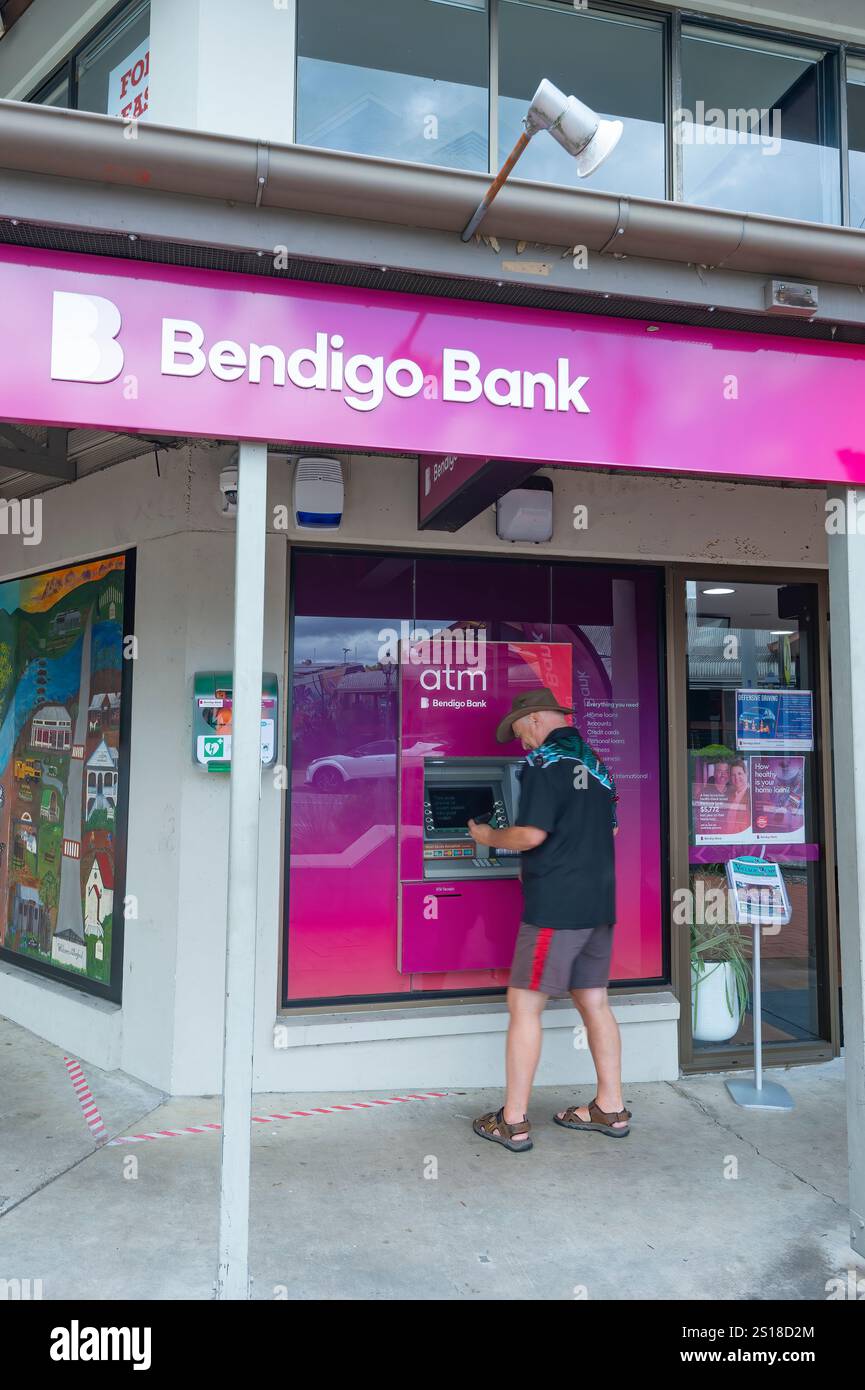 Persona in piedi presso lo sportello Bancomat di Bendigo Bank, Stamford Village, Stamford Valley, Queensland, QLD, Australia Foto Stock