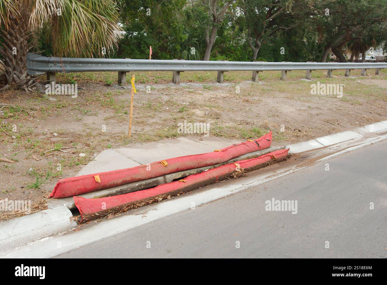 Due barriere di protezione dell'ingresso dello scarico della tempesta rossa intorno alla fogna sul lato della strada. Linee principali lungo marciapiede e strada. Progettato per intrappolare i componenti più pesanti Foto Stock