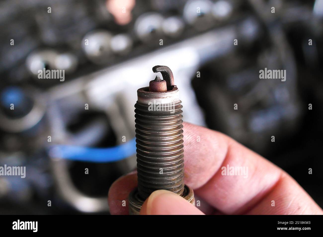 Primo piano della candela usata in mano , candela per auto per sistema di accensione del motore , concetto di parti automobilistiche Foto Stock