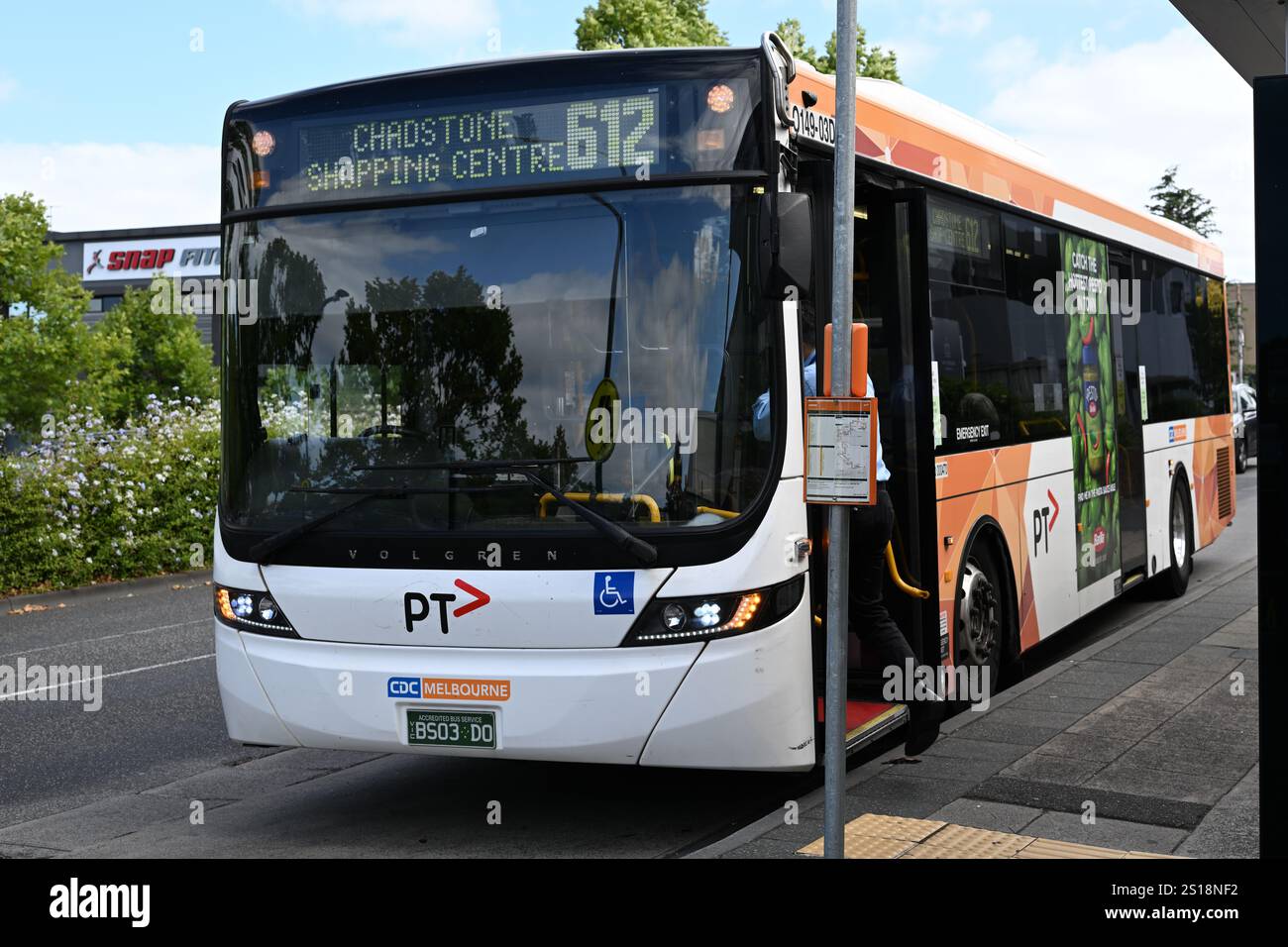 Vista frontale dell'autobus Scania K310UB, con luci di emergenza accese, parcheggiato presso una fermata dell'autobus mentre l'autista sale mentre è oscurato dalla segnaletica della fermata dell'autobus Foto Stock