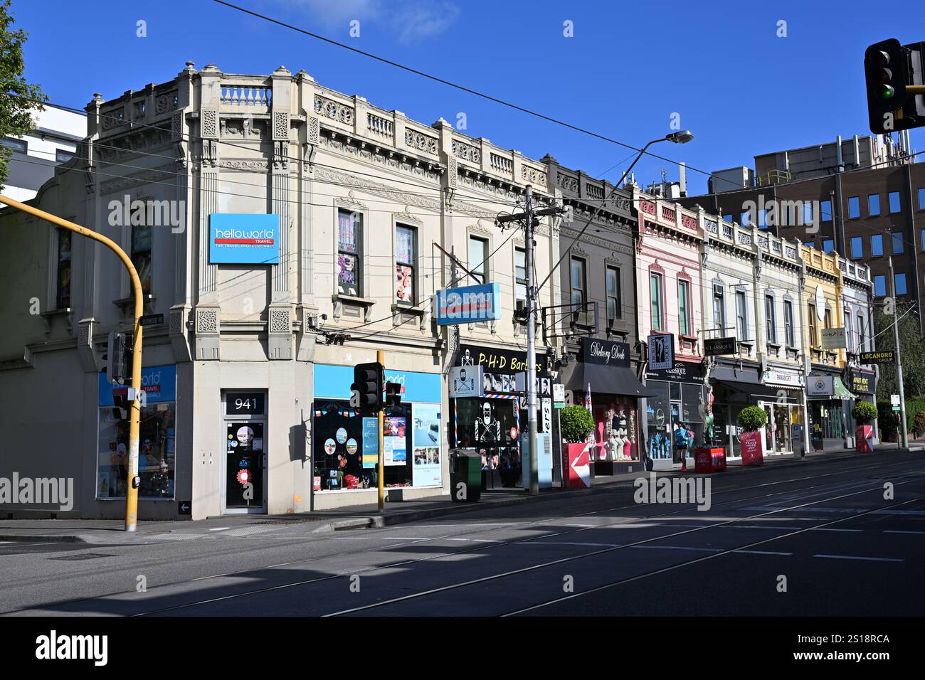 Fila illuminata dal sole di negozi e aziende, tra cui Helloworld Travel, in un vecchio edificio storico lungo Burke Rd, vicino a Camberwell Junction Foto Stock