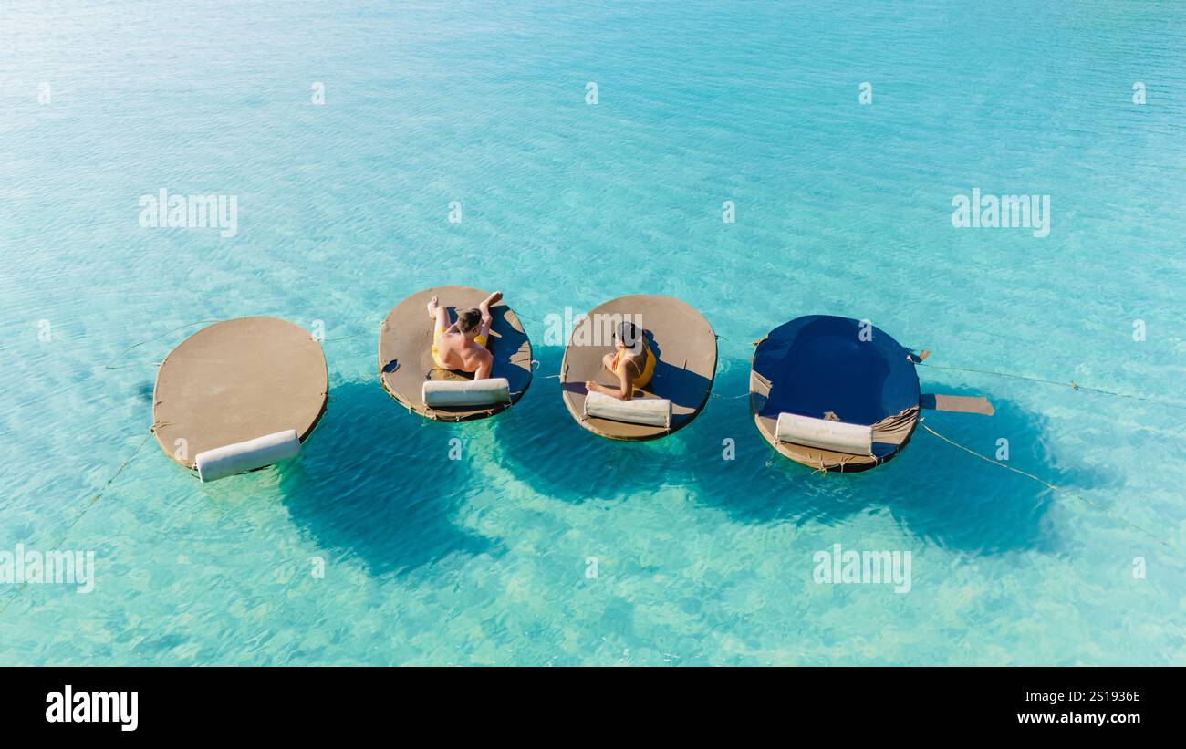 Due amici si godranno un pomeriggio tranquillo su lettini galleggianti, crogiolandosi al sole sopra le acque cristalline di Koh Kood. Circondati da un paesaggio tranquillo che invita al relax e alla pace. Foto Stock