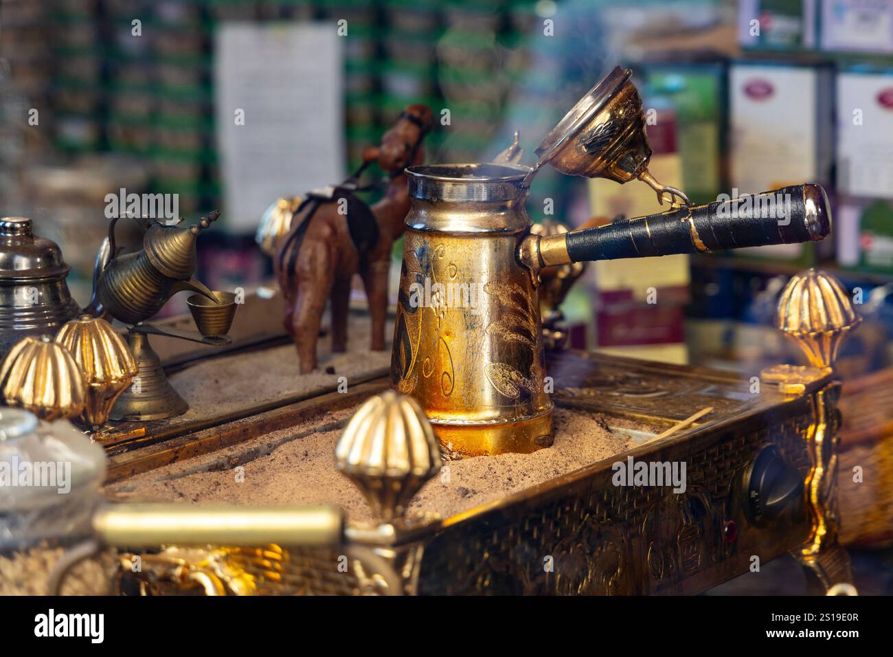 Caffè arabo estratto in una dallah (caffettiera araba) su sabbia calda Foto Stock