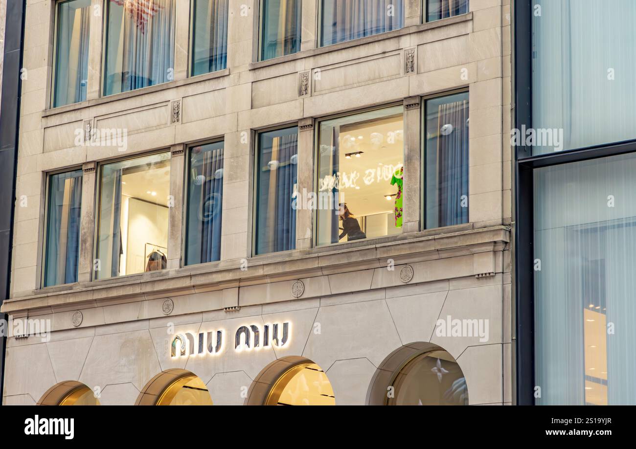 una donna che lavora in una finestra al secondo piano sulla 57esima strada est, new york Foto Stock