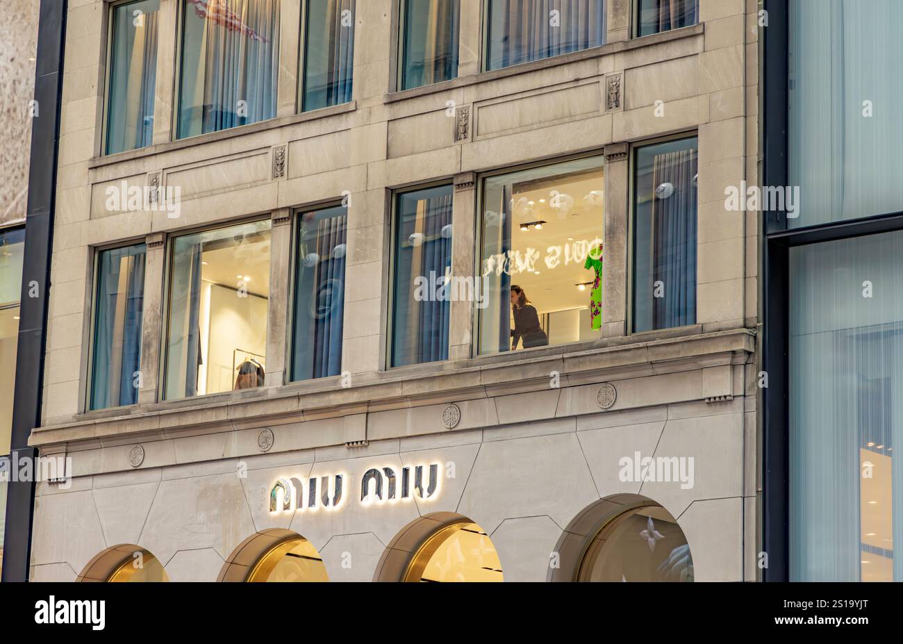 una donna che lavora in una finestra al secondo piano sulla 57esima strada est, new york Foto Stock