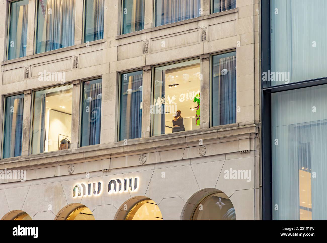 una donna che lavora in una finestra al secondo piano sulla 57esima strada est, new york Foto Stock