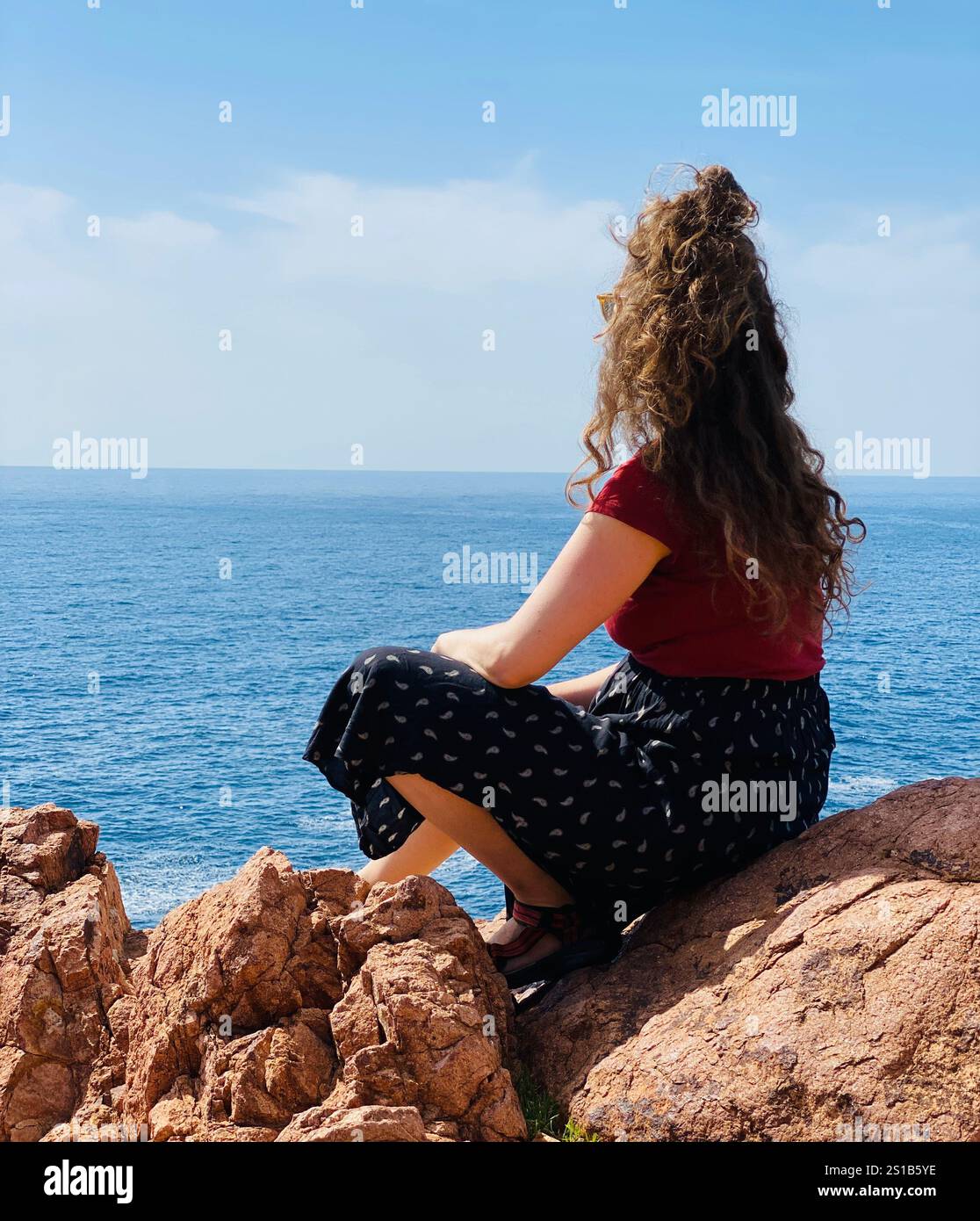 Una donna seduta sulle rocce vicino alla Costa Azzurra, in Francia Foto Stock