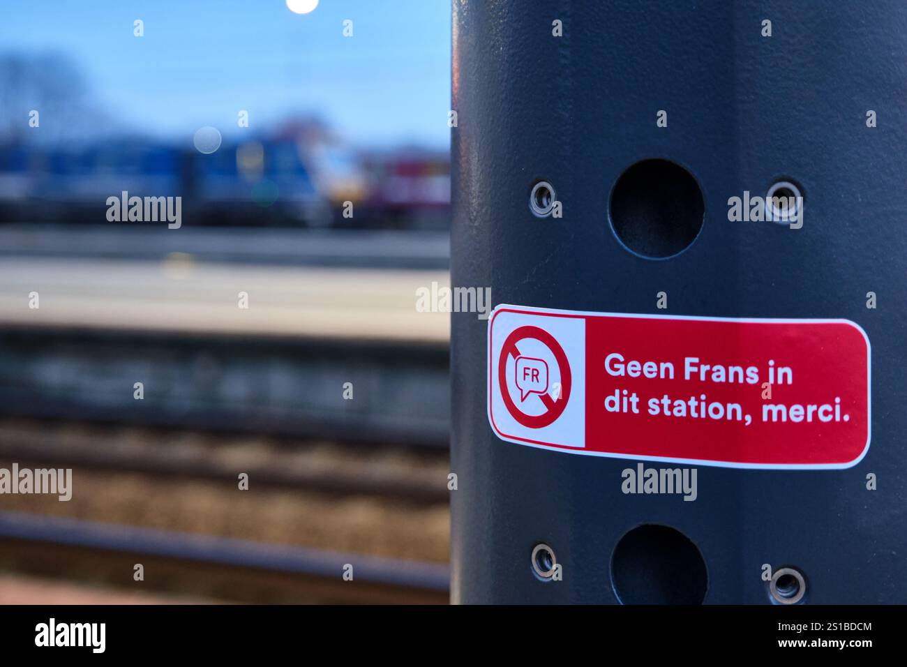 Un adesivo sulla piattaforma ferroviaria di Vilvoorde che protesta contro l'uso della francese sui treni NMBS nelle Fiandre. Secondo la legge, solo l'olandese può essere usato Foto Stock