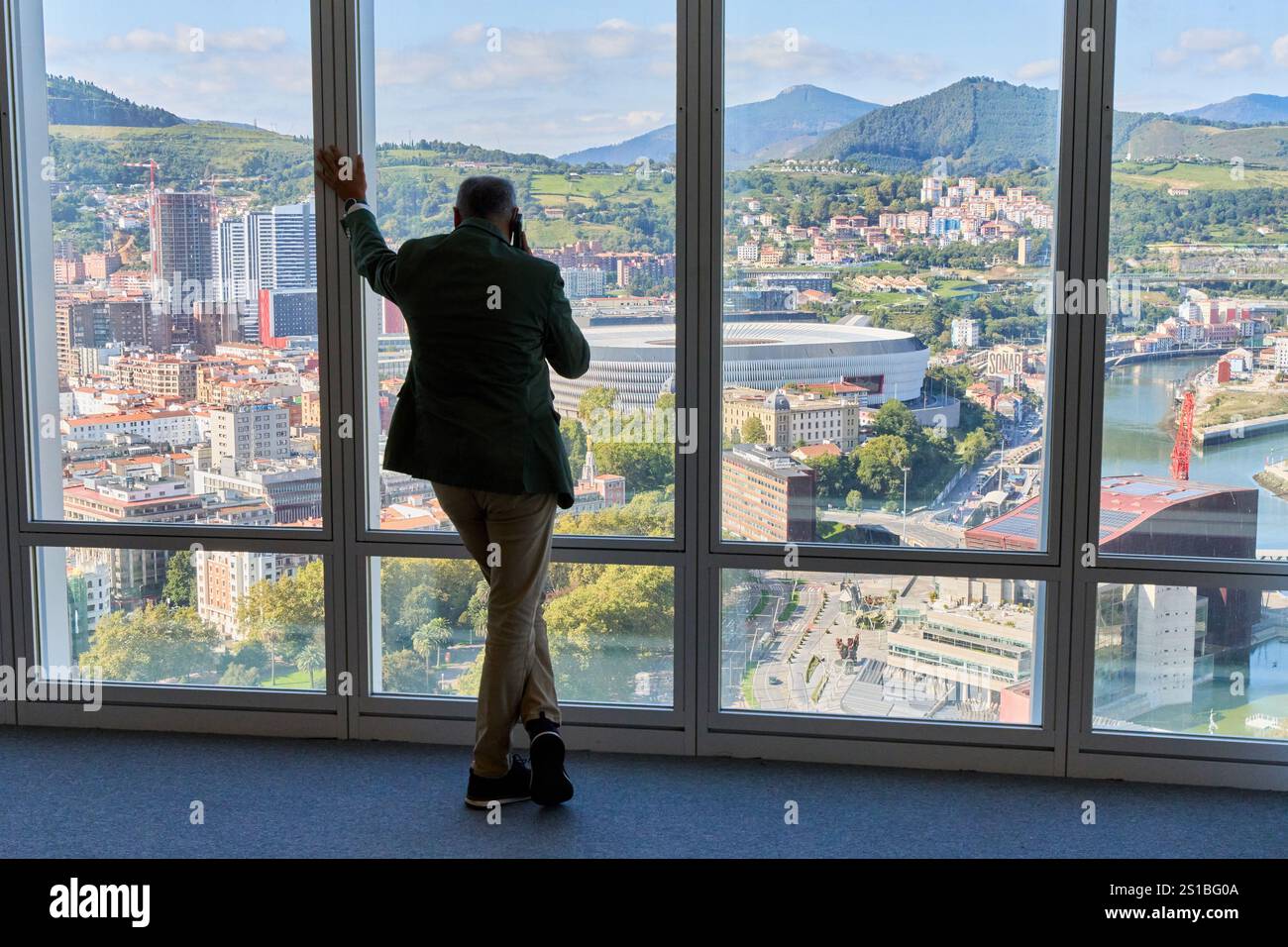 Uomo d'affari che parla al telefono, guarda la città, lo stadio di San Mames, il palazzo Euskalduna, viste dalla Torre Iberdrola, Bilbao, Paesi Baschi, Spagna Foto Stock