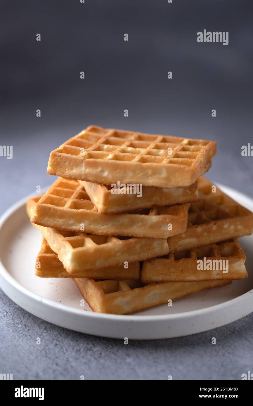 Foto Crisp e Golden waffle Stack su un piatto: Colazione preparata alla perfezione pronta per iniziare la giornata o per un dolce pasto Foto Stock