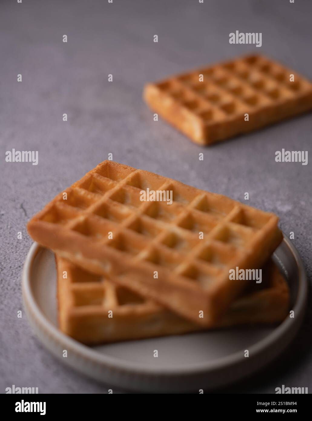 Fotografa deliziosi waffle fatti in casa su uno sfondo neutro che ne esalta la consistenza dorata e croccante, perfetti per gli amanti della colazione che cercano un piatto gustoso e semplice Foto Stock
