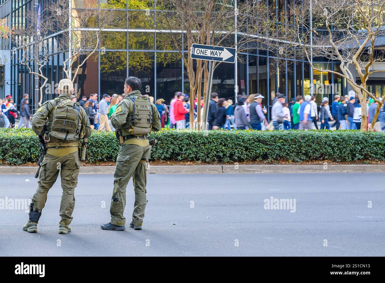 New Orleans, LOUISIANA, USA - 2 gennaio 2025: La polizia della sicurezza Nazionale sta di guardia su Poydras Street vicino al Superdome mentre i tifosi di football si dirigono verso lo Sugar Bowl sullo sfondo un giorno dopo che il camion terroristico è stato arato nella folla di Bourbon Street uccidendo almeno 14 persone. Foto Stock