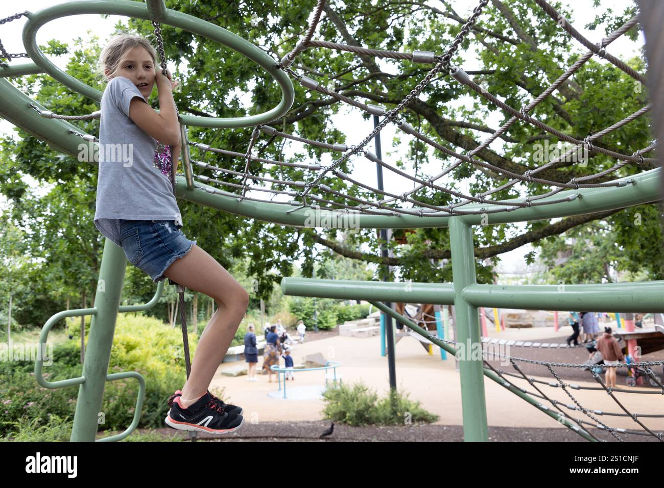 Una bambina di otto anni è appesa su una cornice per arrampicarsi in un parco giochi in un nuovo sviluppo a Brent Cross. Foto Stock
