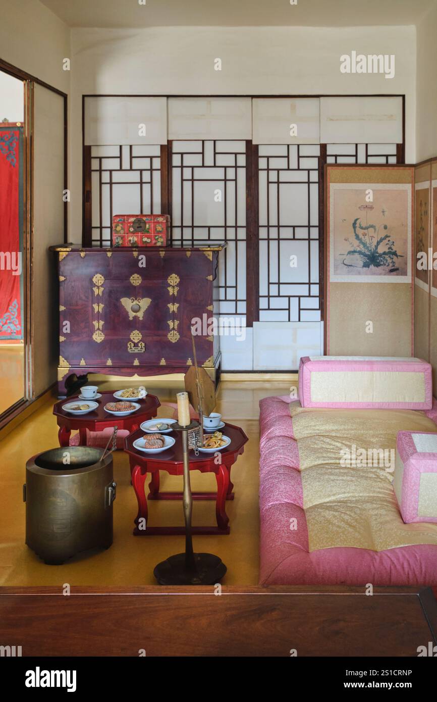 Camera Royal con petto in legno, cuscini rosa, un set di tè. Vista interna presso il museo Unhyeongung Royal Residence a Seoul, Corea del Sud. Foto Stock