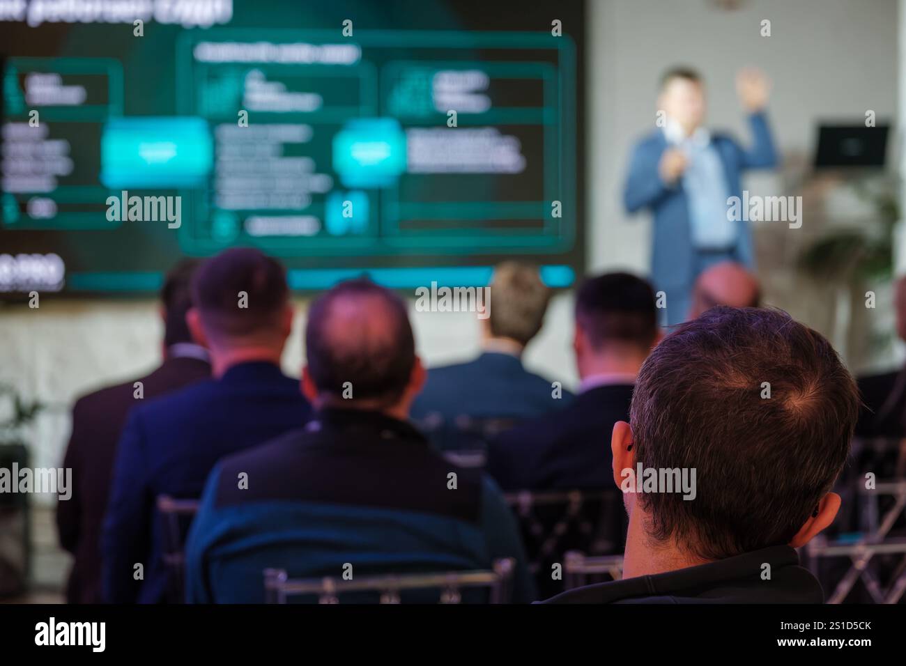 Presentazione professionale a un pubblico attento in una conferenza. Concentrarsi sull'altoparlante e sullo schermo con le informazioni visualizzate. Foto Stock