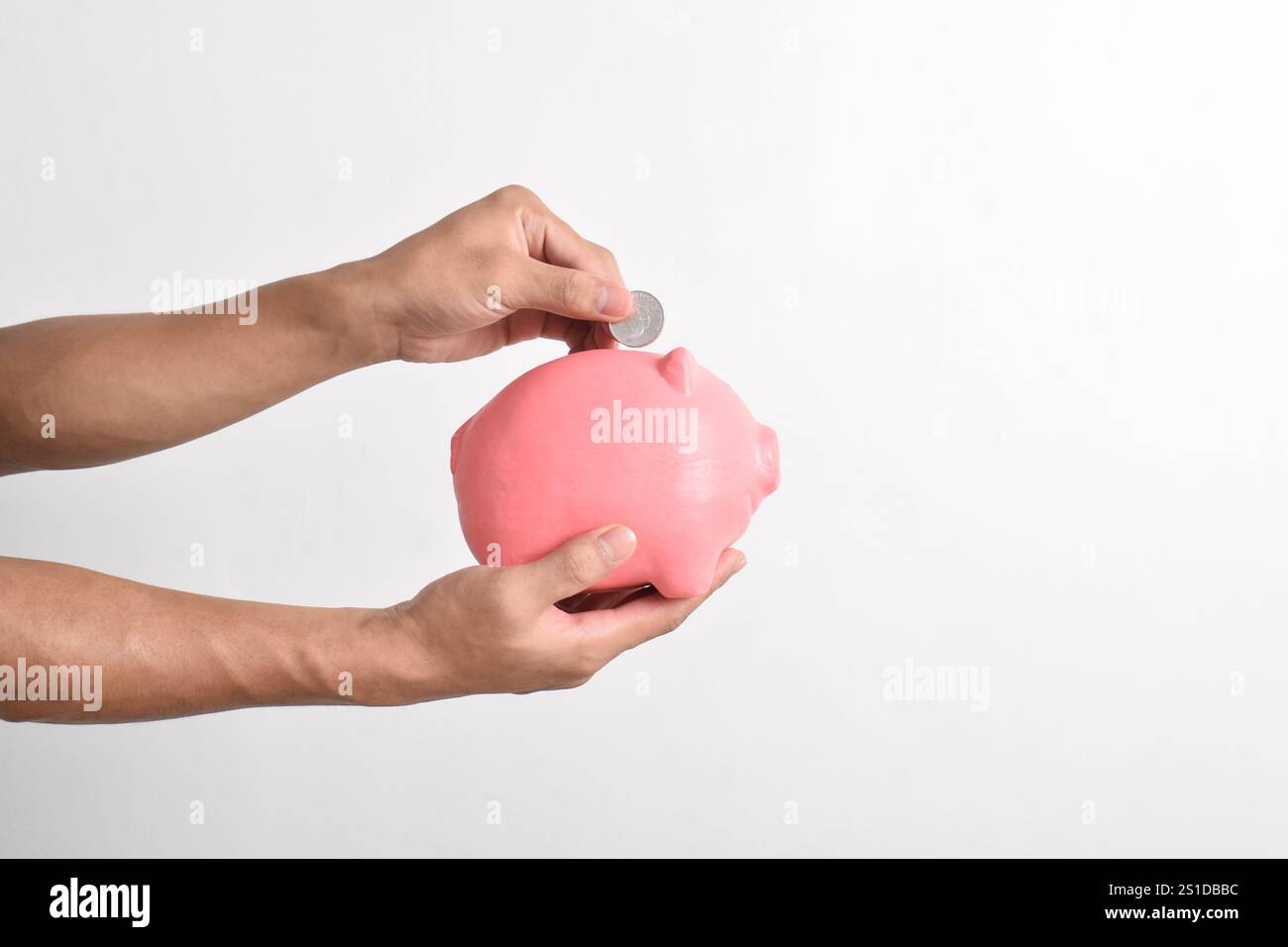 Mano che mette le monete nel salvadanaio isolato su sfondo bianco. Risparmio di denaro per il fondo pensione e il concetto di pianificazione futura. Foto Stock