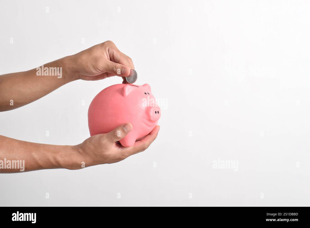 Mano che mette le monete nel salvadanaio isolato su sfondo bianco. Risparmio di denaro per il fondo pensione e il concetto di pianificazione futura. Foto Stock