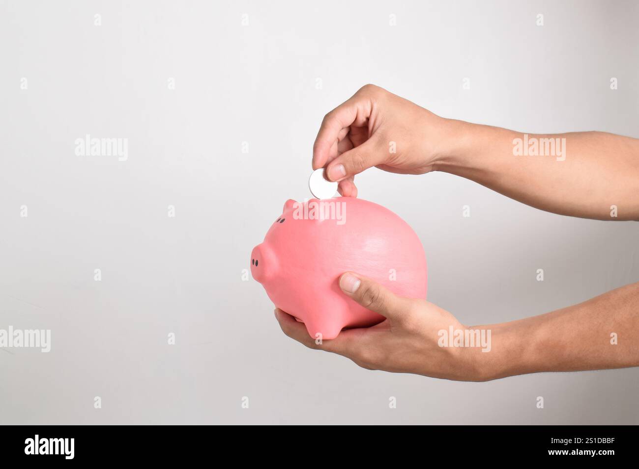 Mano che mette le monete nel salvadanaio isolato su sfondo bianco. Risparmio di denaro per il fondo pensione e il concetto di pianificazione futura. Foto Stock