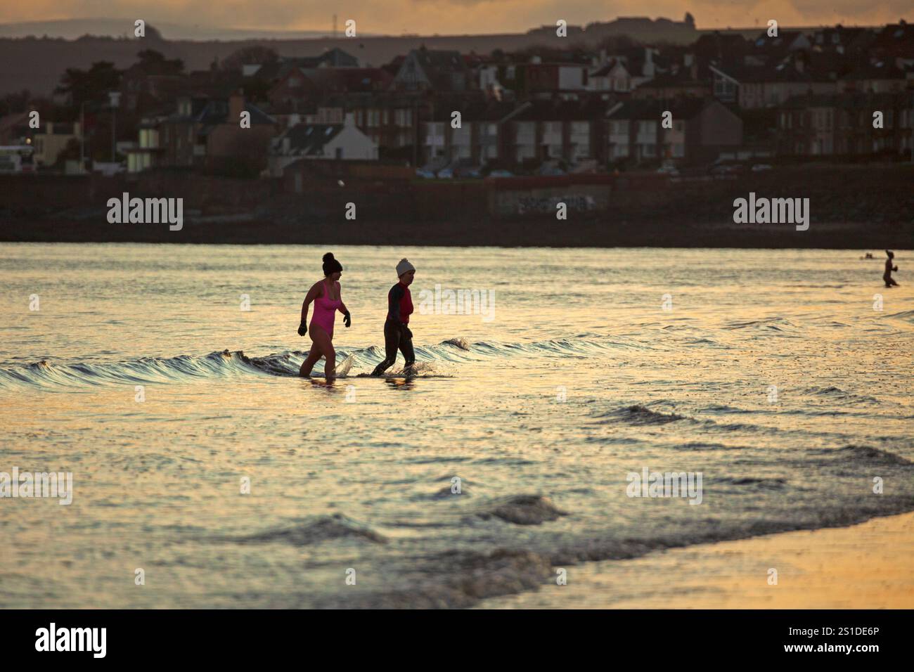 Portobello, Edimburgo, Scozia, Regno Unito. 3 gennaio 2025. Esercitazione all'alba sul Firth of Forth proprio mentre il sole sorge dietro la nuvola, temperatura di un nippy di 1 gradi centigradi. Due nuotatori d'acqua fredda lasciano il Firth of Forth dopo un bagno tonificante. Credito: Arch White/alamy notizie dal vivo. Foto Stock