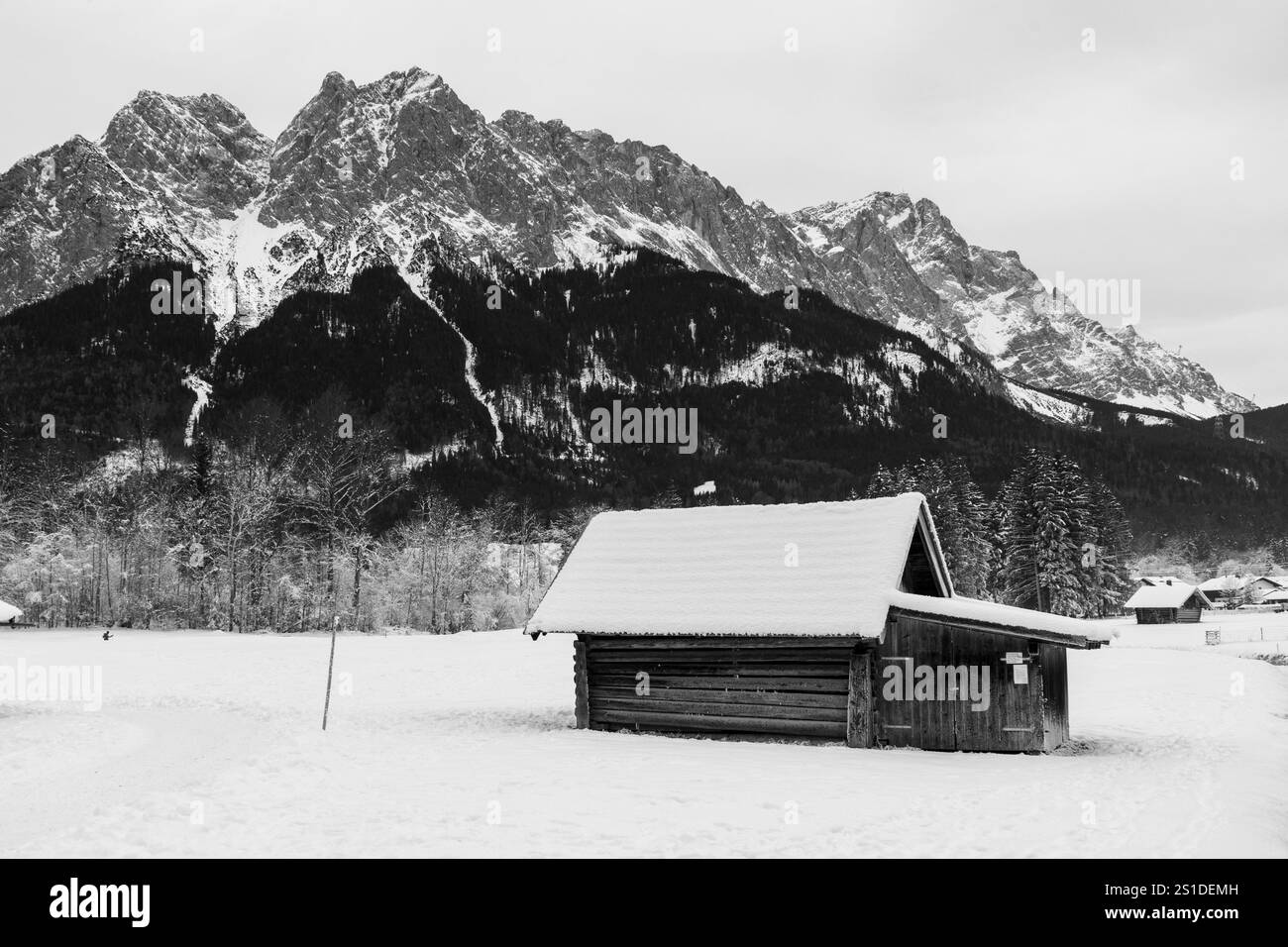 Vecchia casa in legno ai piedi dello Zugspitze nelle Alpi, fotografia in bianco e nero Foto Stock