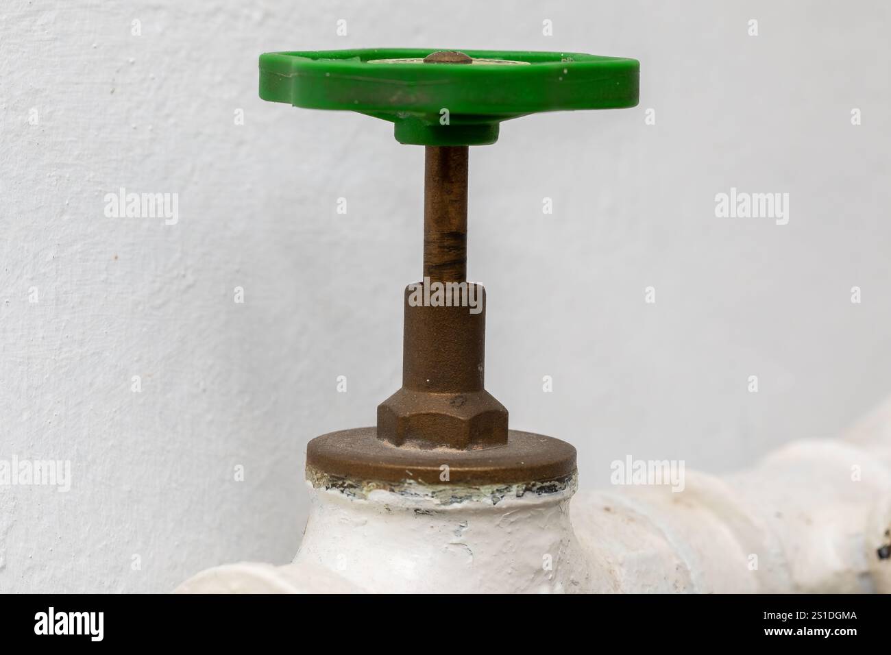 Valvola di arresto su un tubo contro una parete bianca - primo piano di tubazioni industriali Foto Stock