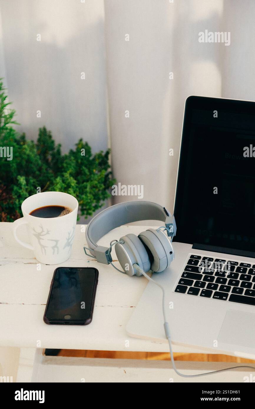 Comodo spazio di lavoro con caffè, cuffie e laptop Foto Stock