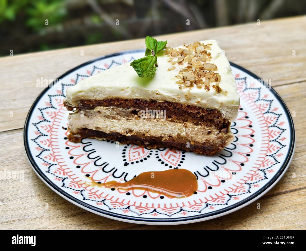 Un piatto di torta di carote servito con glassa di formaggio spalmabile, noci tritate, salsa al caramello e foglie di menta Foto Stock