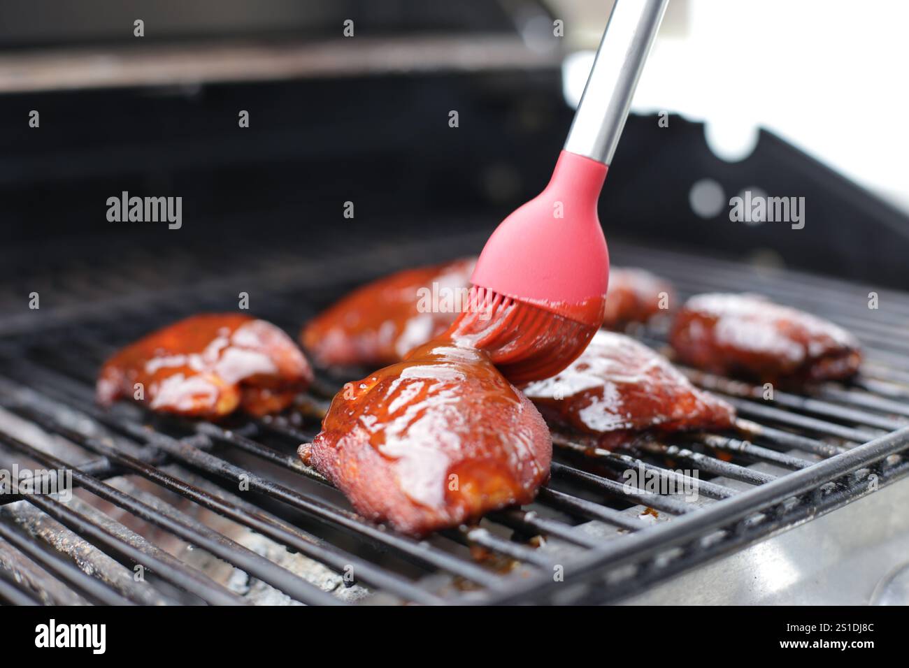 Cosce di pollo su una griglia, con salsa barbecue Foto Stock