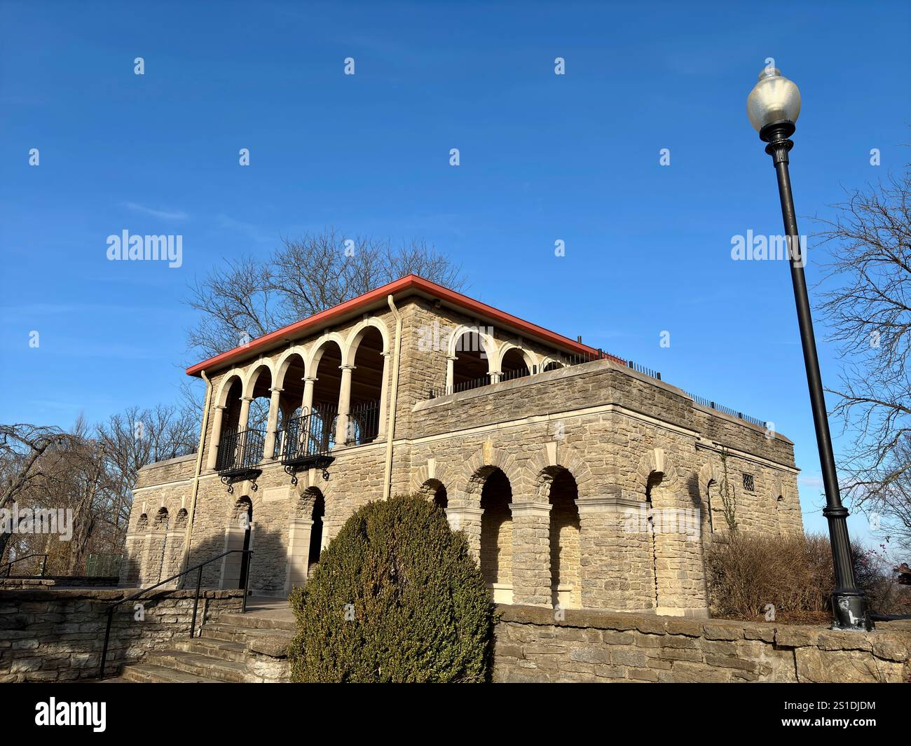 Edificio storico in pietra con finestre ad arco, tetto rosso sotto il cielo blu Foto Stock