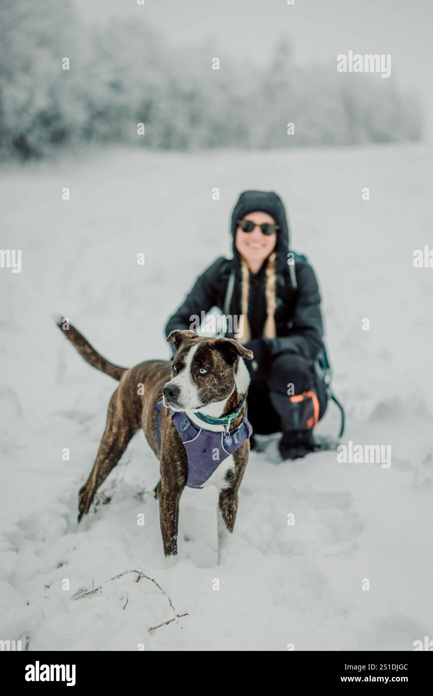 una donna che posa con il cane mentre cammina nella neve, maine. Foto Stock