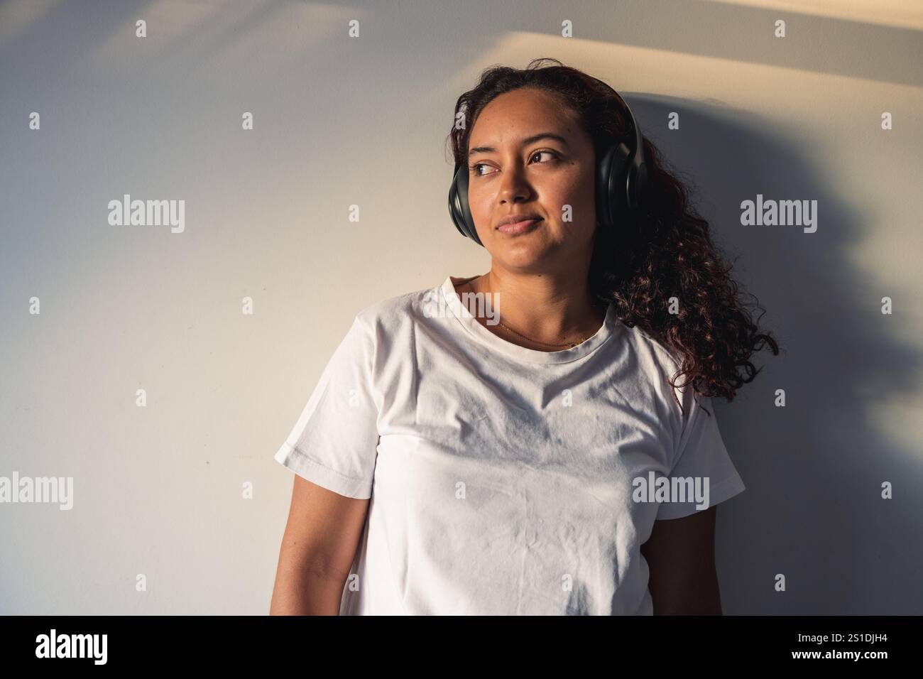 Donna rilassata che ascolta musica con le cuffie a casa Foto Stock