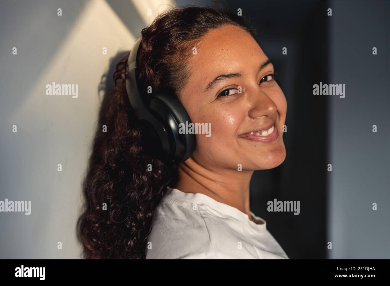 Giovane donna sorridente e sicura di sé con le cuffie che guardano alla telecamera Foto Stock