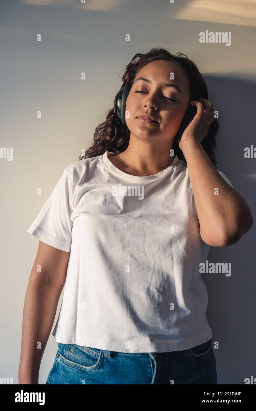 Donna rilassata che ascolta musica con le cuffie a casa Foto Stock